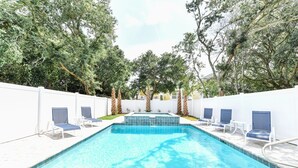 Une piscine rectangulaire bordée de carreaux, entourée de murs blancs et de palmiers.