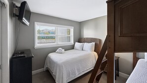 A bedroom with a bed, a television mounted on the wall, and a window with blinds. - 111 El Matador 2 Bedroom Condo by RedAwning (Fort Walton Beach)