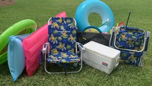 A grassy area with a pool float, a beach chair, a cooler, and a beach bag. - 111 El Matador 2 Bedroom Condo by RedAwning (Fort Walton Beach)