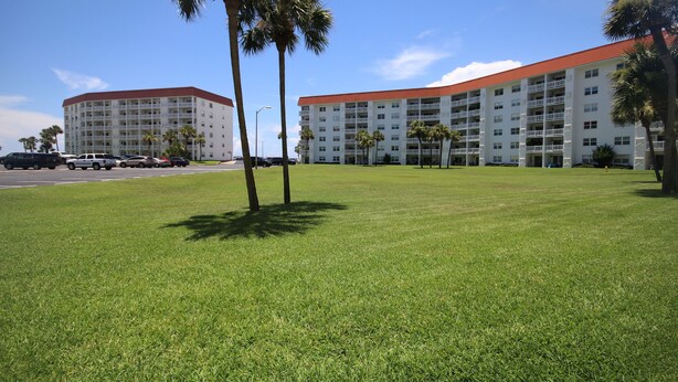 A hotel with a red roof and multiple balconies, surrounded by a well-maintained lawn and palm trees. - 111 El Matador 2 Bedroom Condo by RedAwning (Fort Walton Beach)