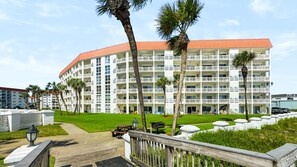 A multi-story hotel with balconies, a well-maintained lawn, and a clear sky. - 111 El Matador 2 Bedroom Condo by RedAwning (Fort Walton Beach)