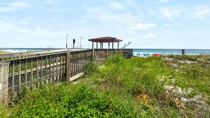 A wooden boardwalk leading to a gazebo with a red roof, overlooking a beach with umbrellas and the ocean. - 111 El Matador 2 Bedroom Condo by RedAwning (Fort Walton Beach)