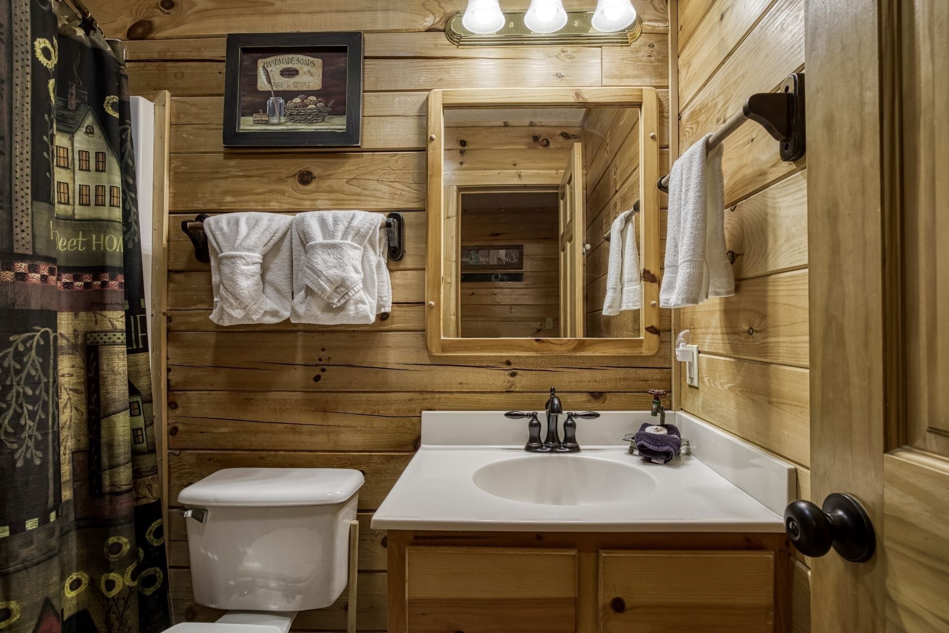 A wooden cabin bathroom with a white sink, a toilet, and a mirror.