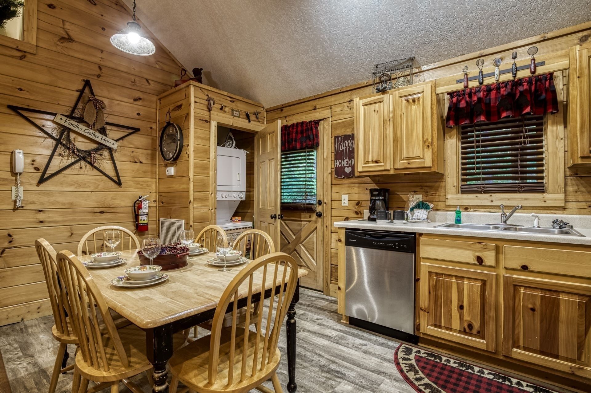 A wooden cabin-style kitchen with a dining table set for four, a dishwasher, and a stove.