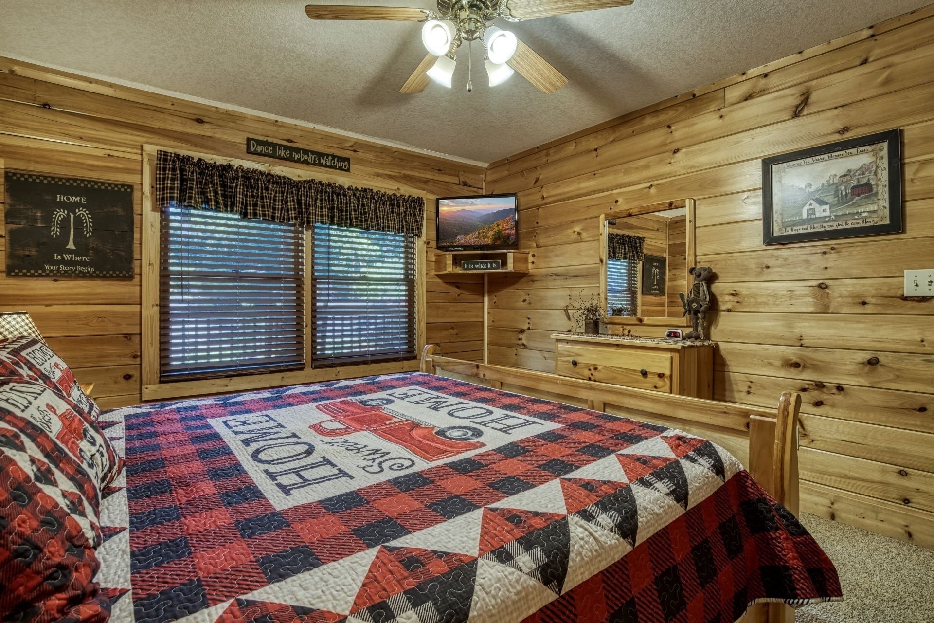 A cozy log cabin bedroom with a bed, a television, and a mirror.