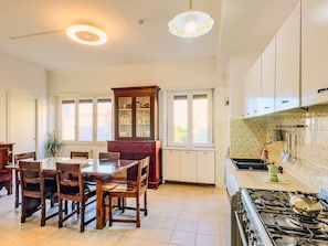 A kitchen with a dining table, chairs, a stove, cabinets, and a window.