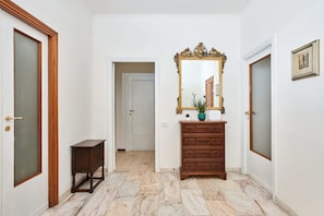 A hallway with a wooden dresser, a mirror, and a door with a frosted glass panel.