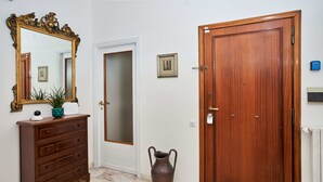 A hallway with a wooden dresser, a large mirror, a vase, and a wooden door. - Luxurious Terrace and confort close Rome Center (Roma)