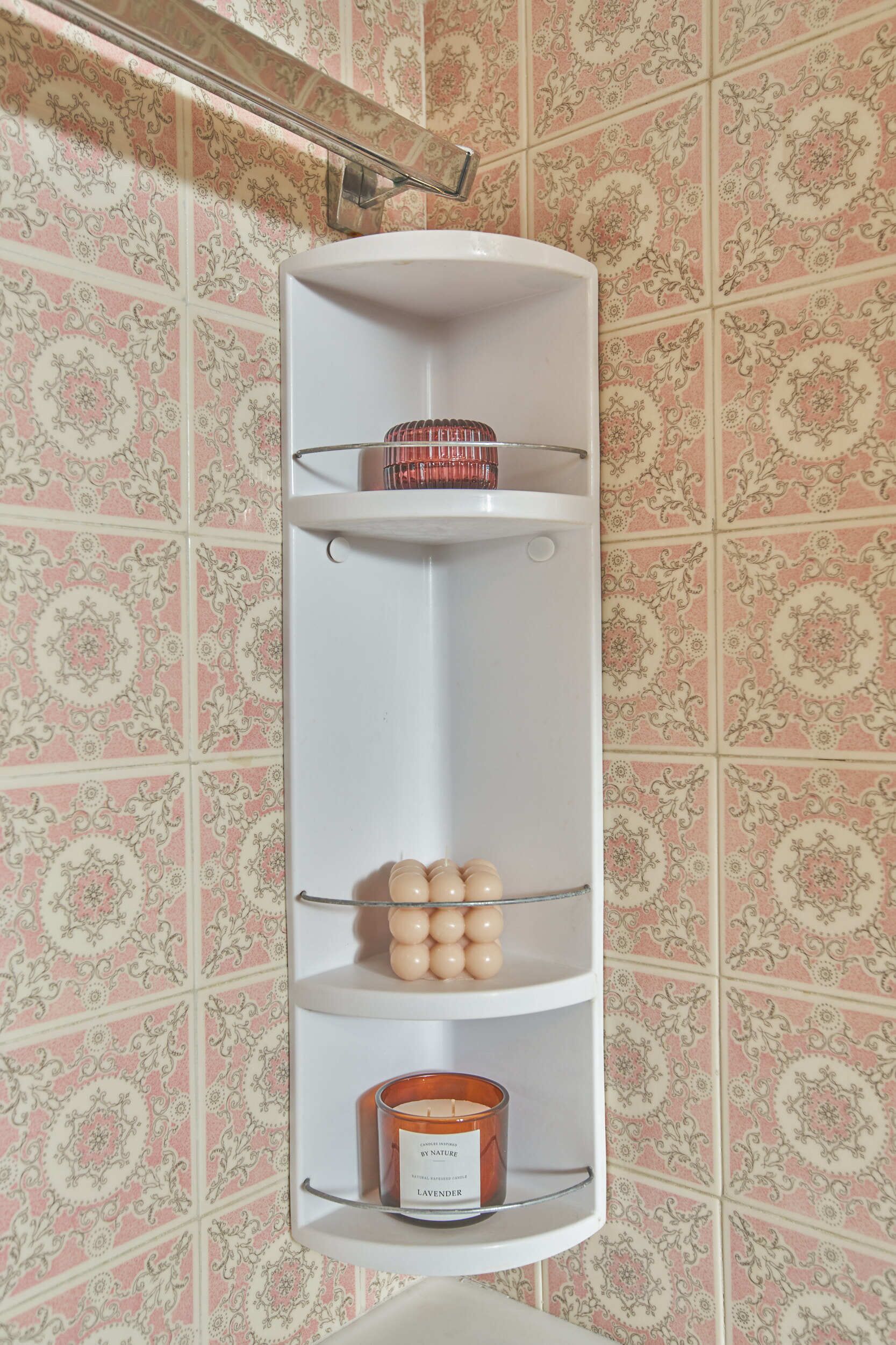 A corner shelf unit with three shelves, one of which holds a candle.