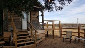 A rustic wooden cabin with a wooden deck, a bench, and a staircase leading to the entrance.