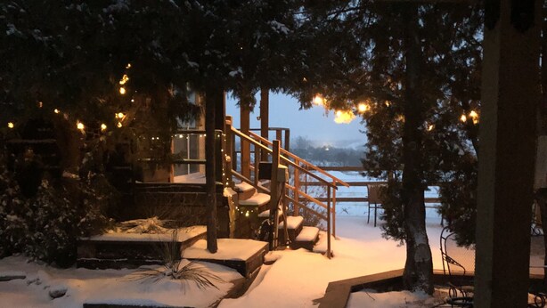 A snow-covered pathway leading to a wooden deck with a sign reading "COYOTE".