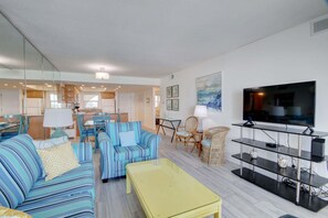 A modern living room with a sofa, chairs, a TV, and a dining area. - 363 El Matador 2 Bedroom Condo by RedAwning (Fort Walton Beach)
