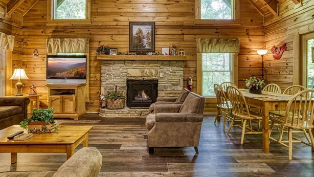 A log cabin interior with a stone fireplace, wooden furniture, and a television. - Er215 - Red Bird Haven Great Location - Close To Town! 3 Bedroom Cabin by RedAwning (Pigeon Forge)