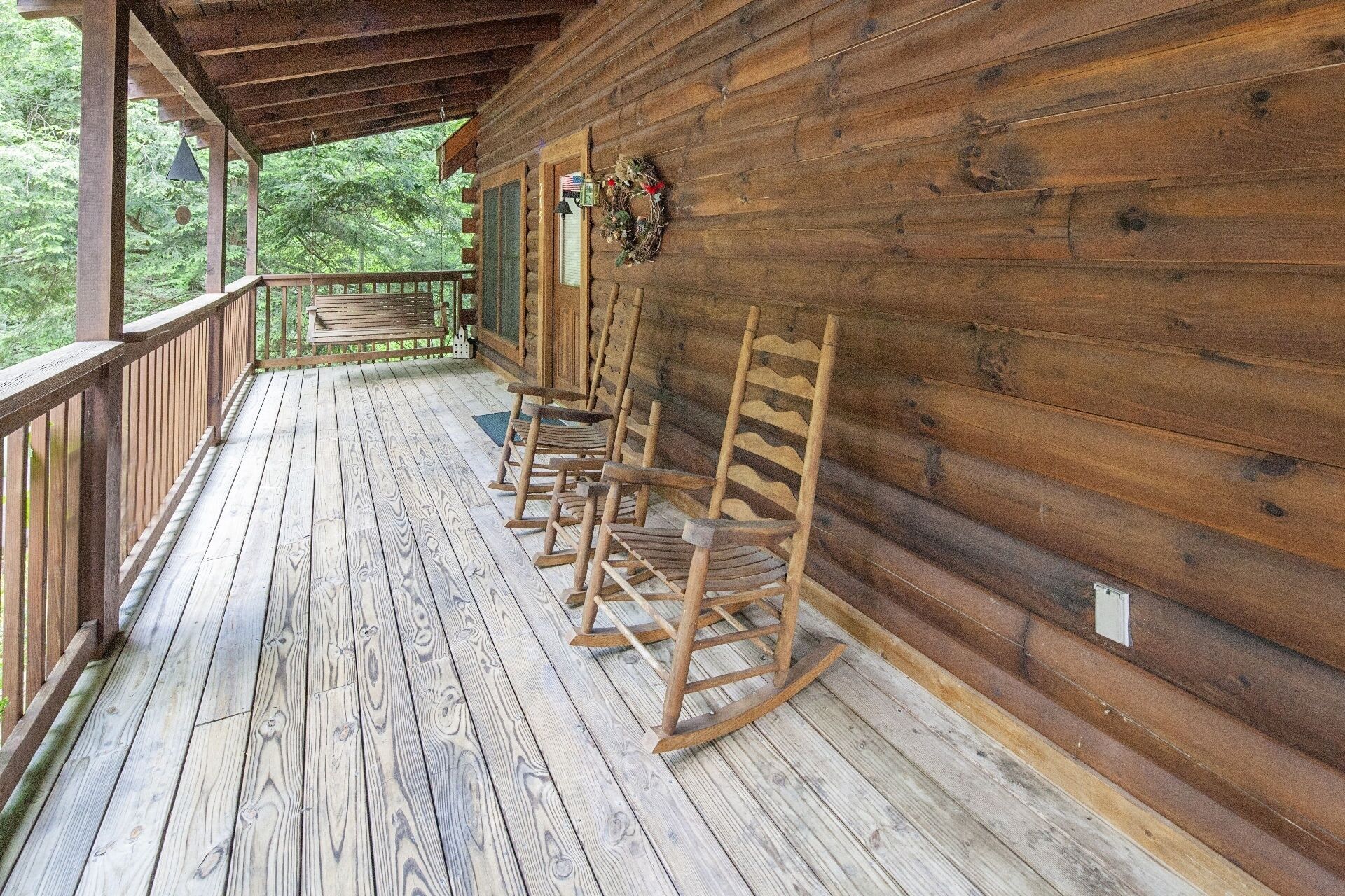 Eine Holzveranda mit einer Bank und mehreren Schaukelstühlen.