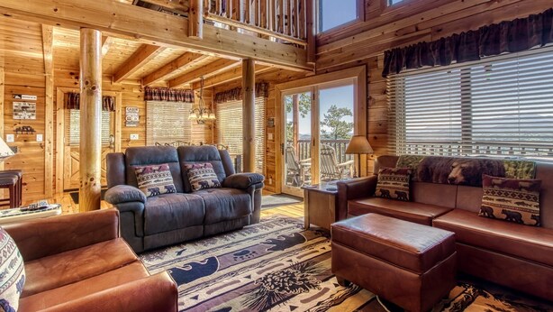 A cabin interior with a wooden interior, a sofa set, a dining area, and a view of the outdoors. - Majestic Mountain View - Great Location! - Convenient To Everything! 2 Bedroom Cabin by RedAwning (Pigeon Forge)