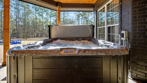 Una vasca idromassaggio con rivestimento in legno, soffitto in legno e vista su una foresta attraverso ampie finestre.