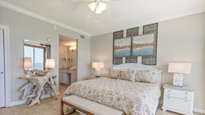 Une chambre à coucher avec un grand lit, un banc, une table de chevet et une coiffeuse avec un miroir.