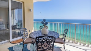 Un balcon avec une table et des chaises, un vase et une vue sur l’océan.