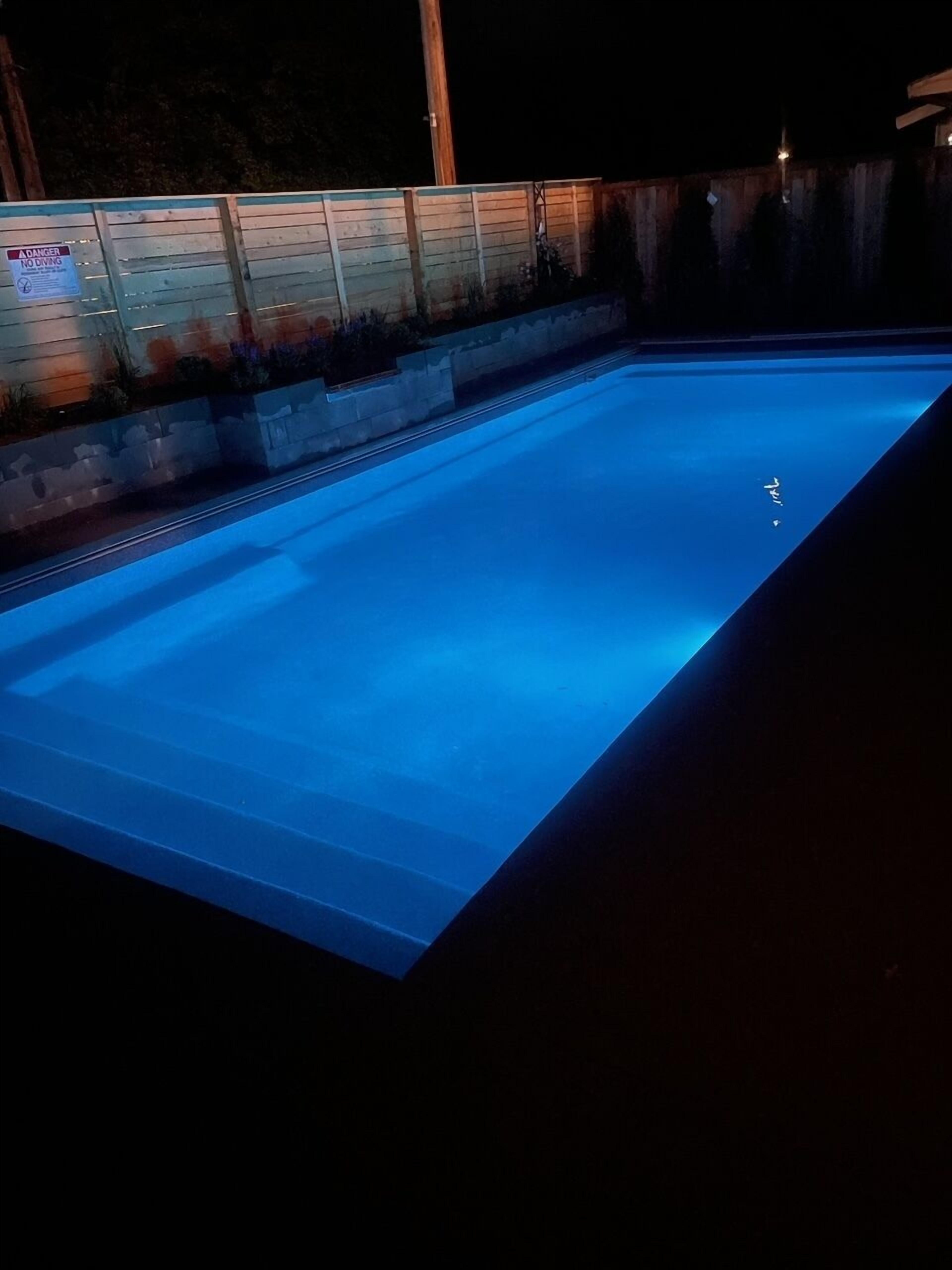 A swimming pool at night with blue lighting.