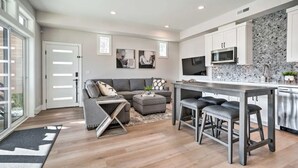 A modern kitchen with white cabinets, a microwave, and a tiled backsplash.