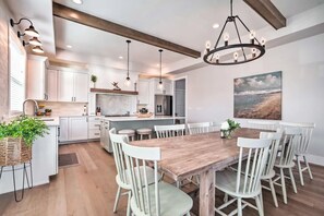 Una cucina moderna con mobili bianchi, un tavolo da pranzo in legno e una grande isola.
