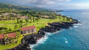 A coastal resort with multiple buildings, a golf course, and a view of the ocean.