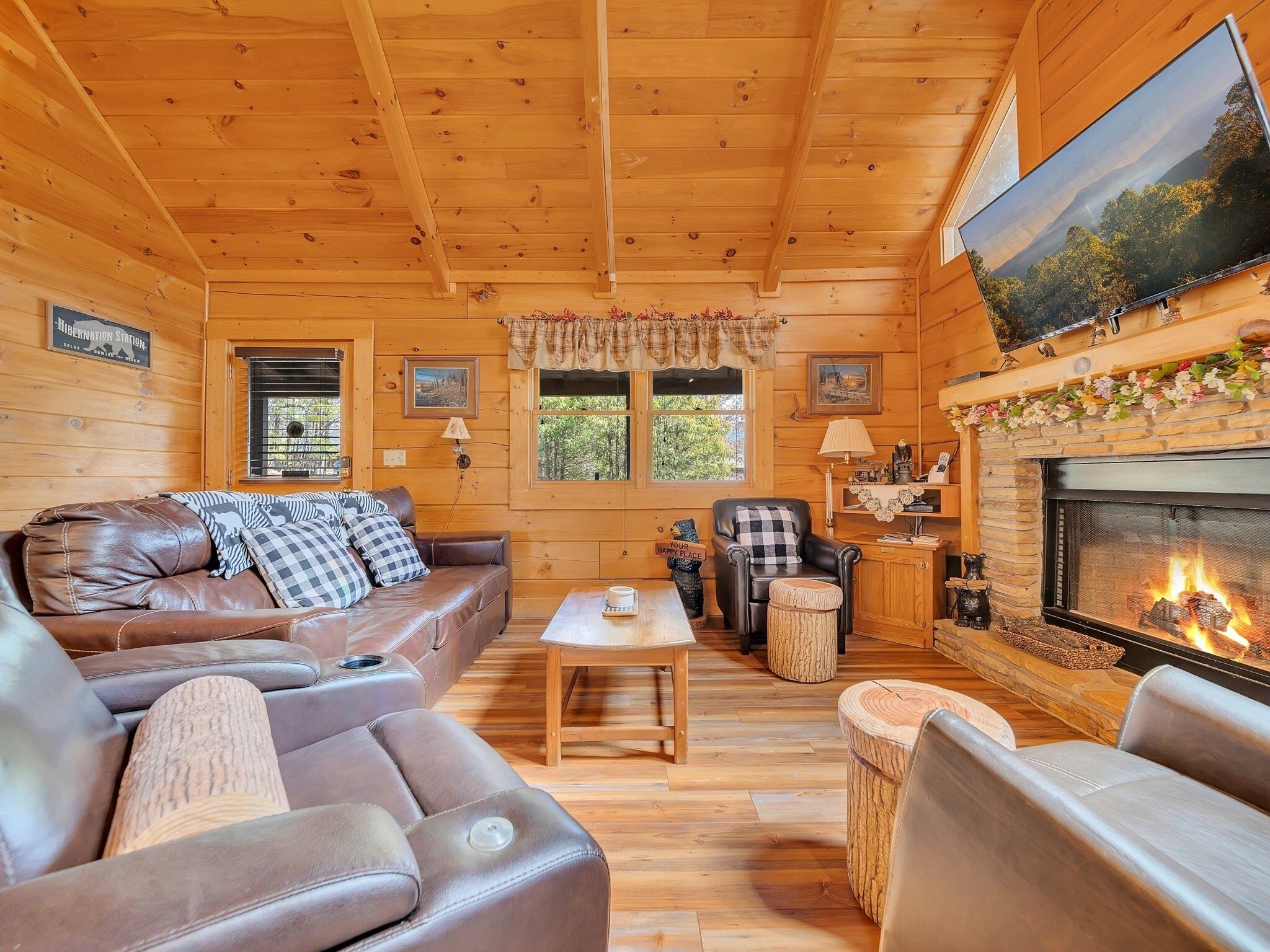 Ein gemütliches Blockhaus-Interieur mit Ledersofa, Kamin und Holzwänden.
