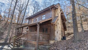 A log cabin with a wooden staircase leading to a deck, surrounded by trees. - Er97 - Squirrel's Retreat - Close To The Action In Pigeon Forge! 2 Bedroom Cabin by RedAwning (Pigeon Forge)