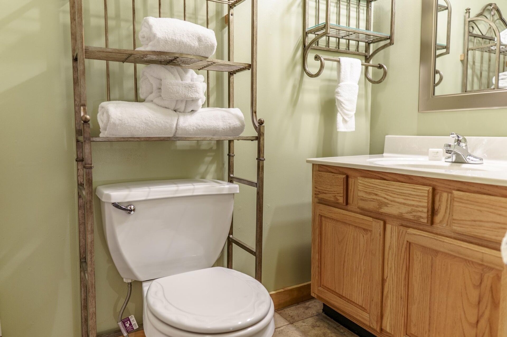 Une salle de bain équipée de toilettes, d’un meuble-lavabo en bois et de porte-serviettes en métal.