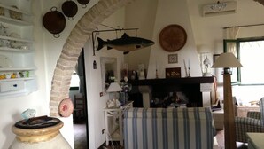 Una sala acogedora con chimenea, un pez colgando del techo y un sofá a rayas.