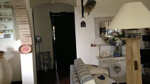 Una sala de estar con un sofá, una lámpara, una decoración de peces y un espejo en la pared.