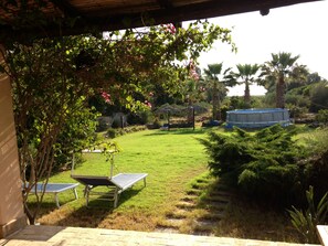 A backyard with a lawn, a pool, and a covered patio area. - La Vignetta Cottage charming house 700 mt from the beach. IUN Q7484 (S.Antioco)