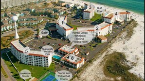 An aerial view of a resort with amenities including a golf course, tennis and pickle ball courts, a seasonal heated pool, and a rental office with a whirlpool, sauna, and fitness room.