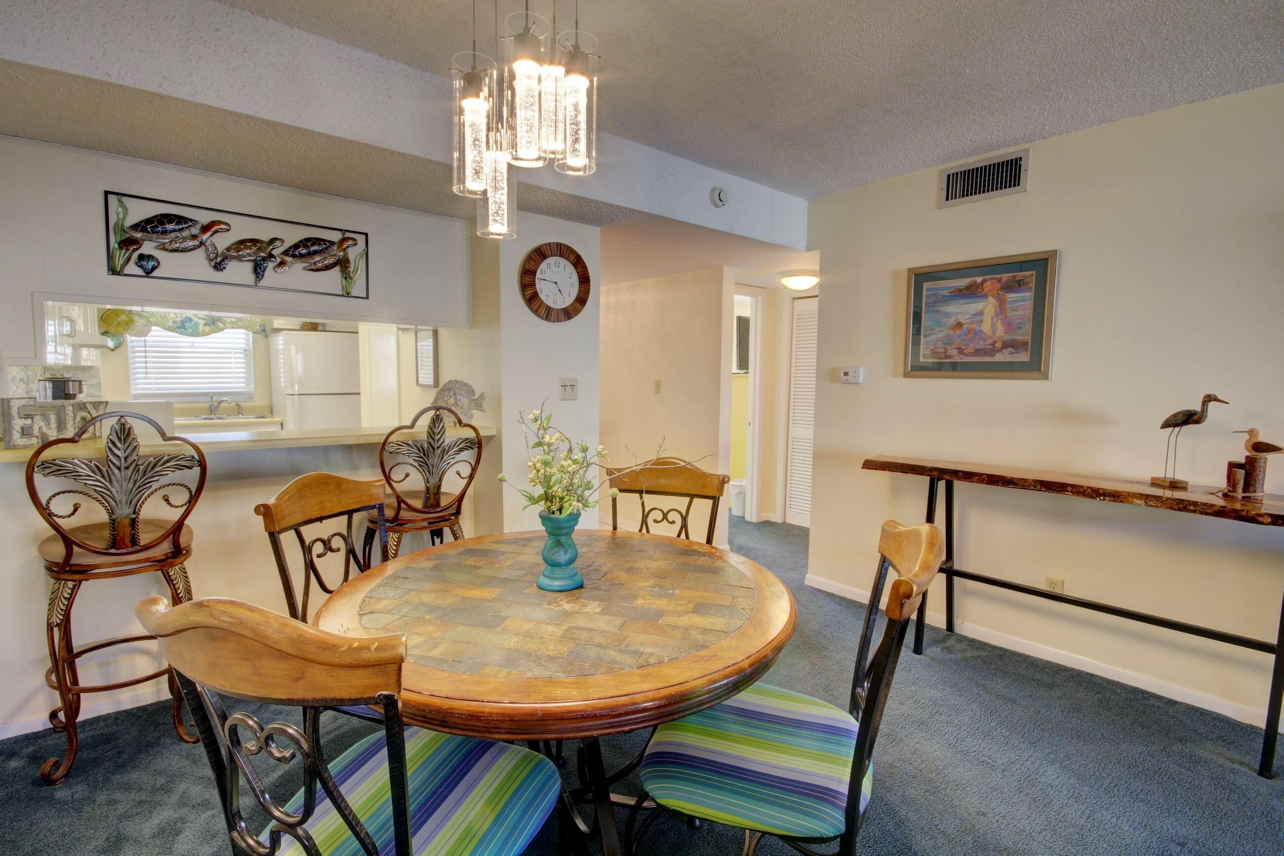 A dining area with a round table, chairs, a vase with flowers, and a chandelier.