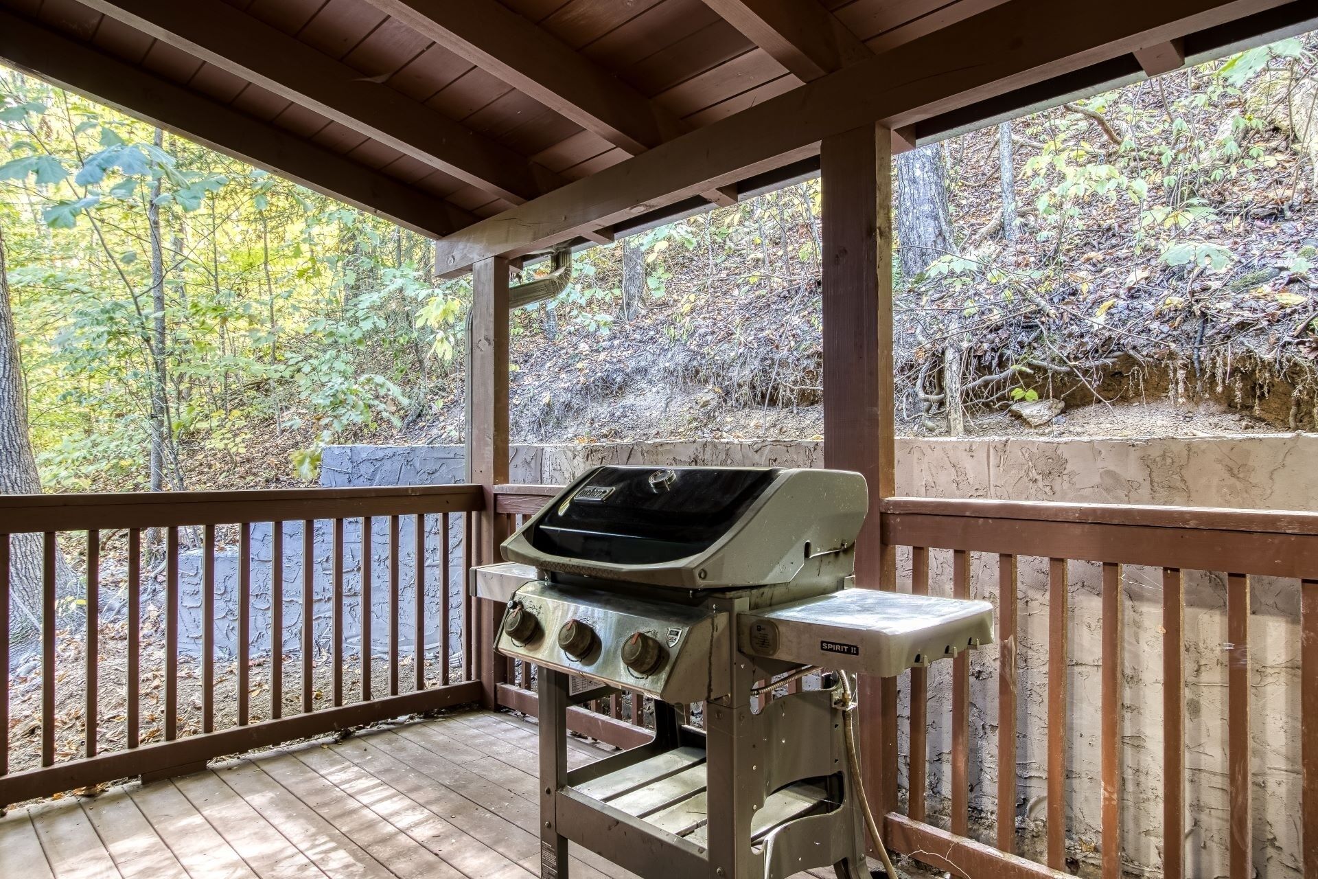 A covered outdoor grill area with a view of a forested area.