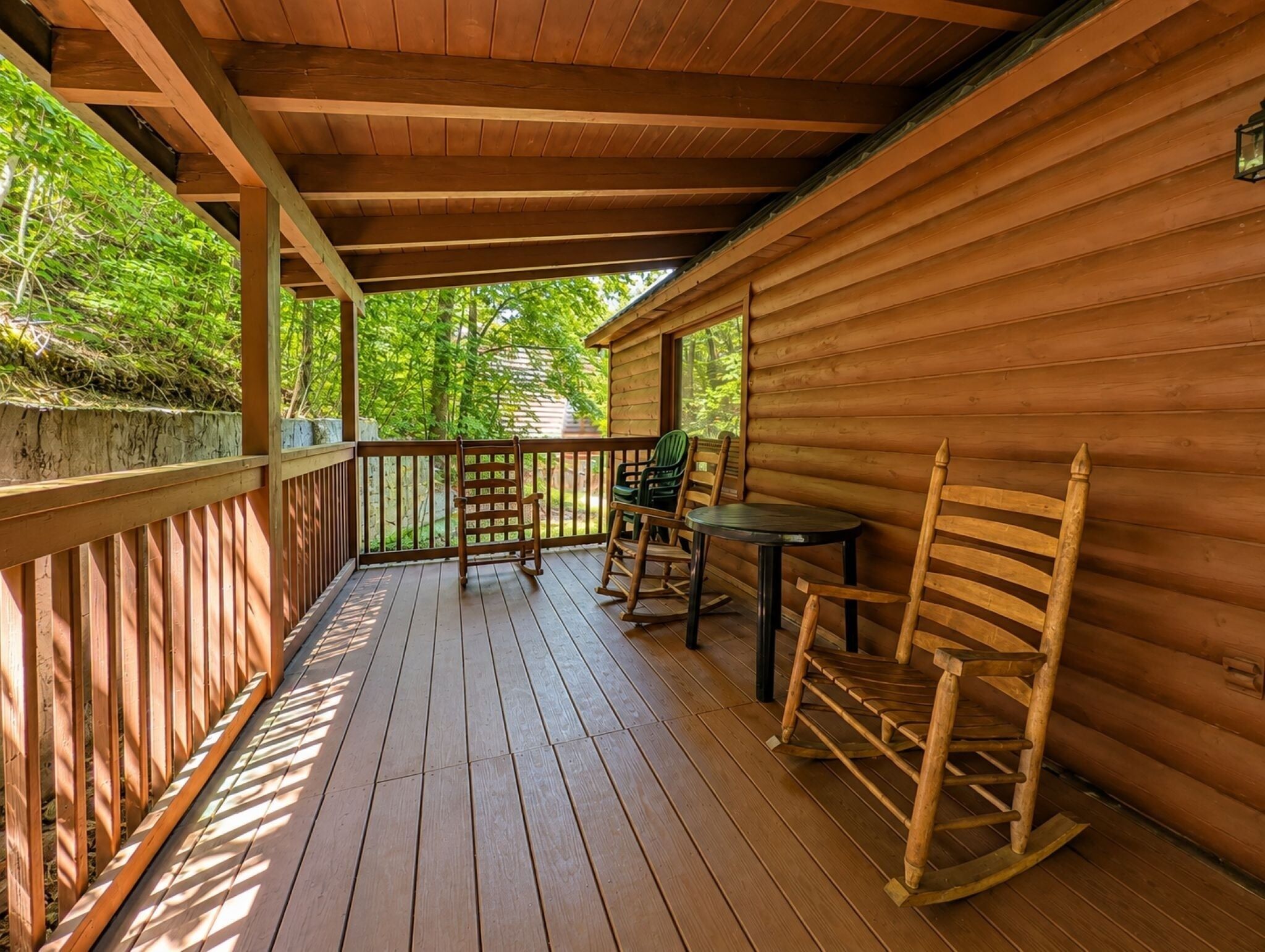 Eine Holzterrasse mit Geländer, einem Tisch und zwei Schaukelstühlen.