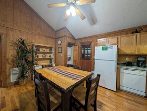 A wooden-paneled kitchen with a dining table, chairs, a refrigerator, and a ceiling fan. - Er38r Grandpa's Getaway - Great Location- Close To Town 2 Bedroom Cabin by RedAwning (Pigeon Forge)