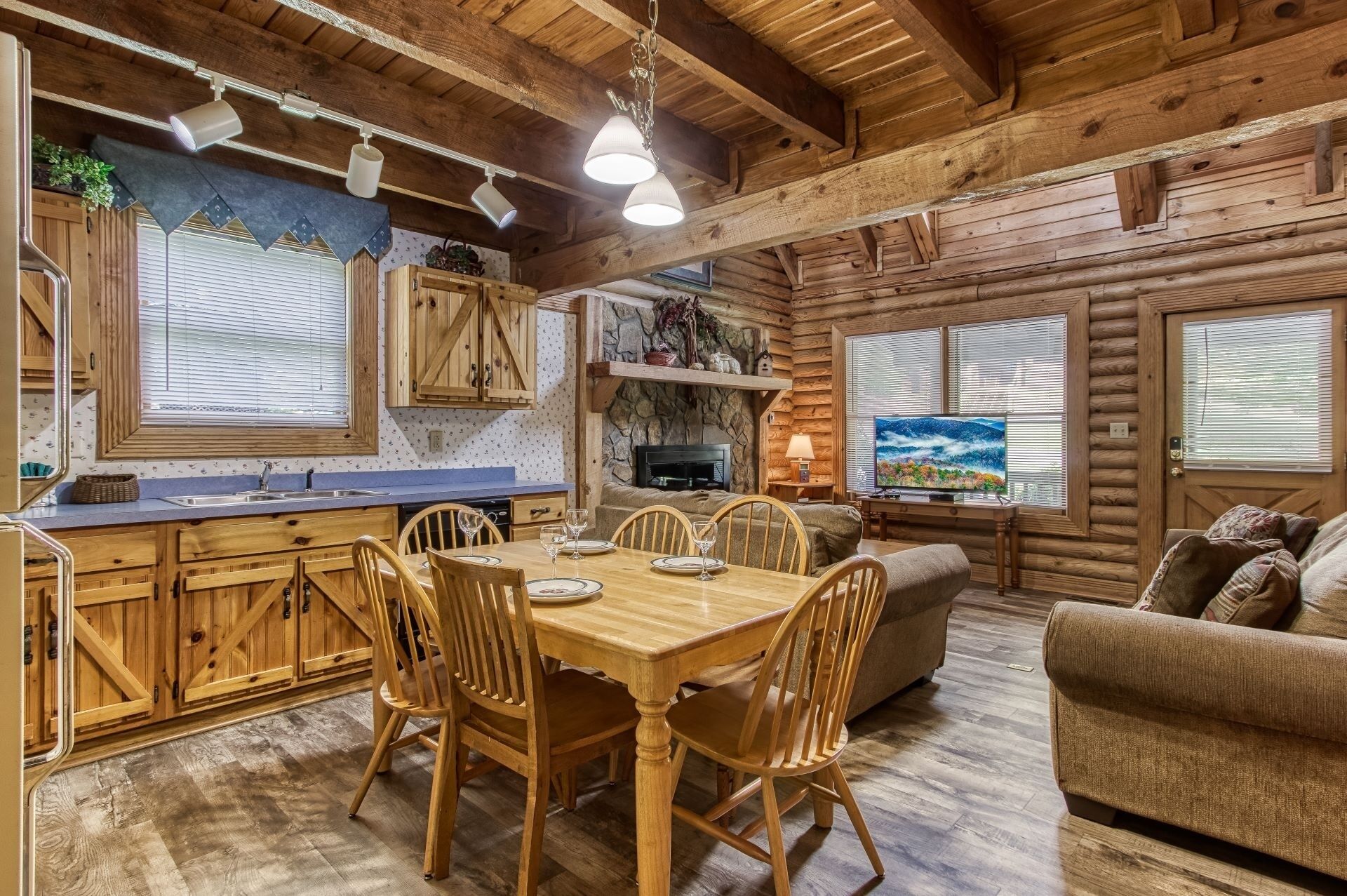 A log cabin interior with a dining area, kitchen, and living room.