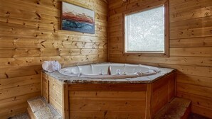 A wooden cabin bathroom with a stone bathtub, a painting on the wall, and a window with blinds. - Ern813 - Heavenly View- Great Location! Close To All The Action! 6 Bedroom Cabin by RedAwning (Sevierville)