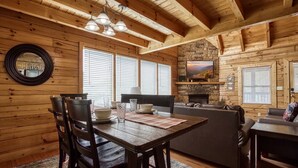 A wooden cabin interior with a dining area, a fireplace, and a stone wall. - Ern813 - Heavenly View- Great Location! Close To All The Action! 6 Bedroom Cabin by RedAwning (Sevierville)