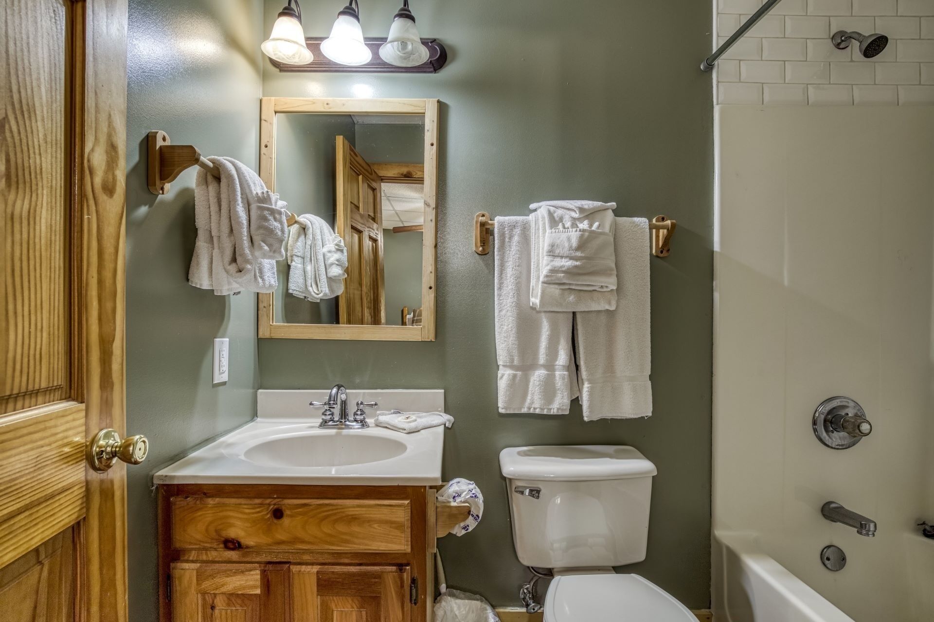 A bathroom with a wooden vanity, a sink, a toilet, and a shower.