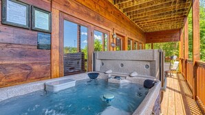 A wooden deck with a hot tub, wooden walls, and a covered area with seating. - Ern857 - A Dream Come True - Great Location! Close To All The Action! 3 Bedroom Cabin by RedAwning (Pigeon Forge)