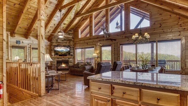 A spacious log cabin interior with a stone fireplace, a large dining area, and a cozy living room. - Ern857 - A Dream Come True - Great Location! Close To All The Action! 3 Bedroom Cabin by RedAwning (Pigeon Forge)