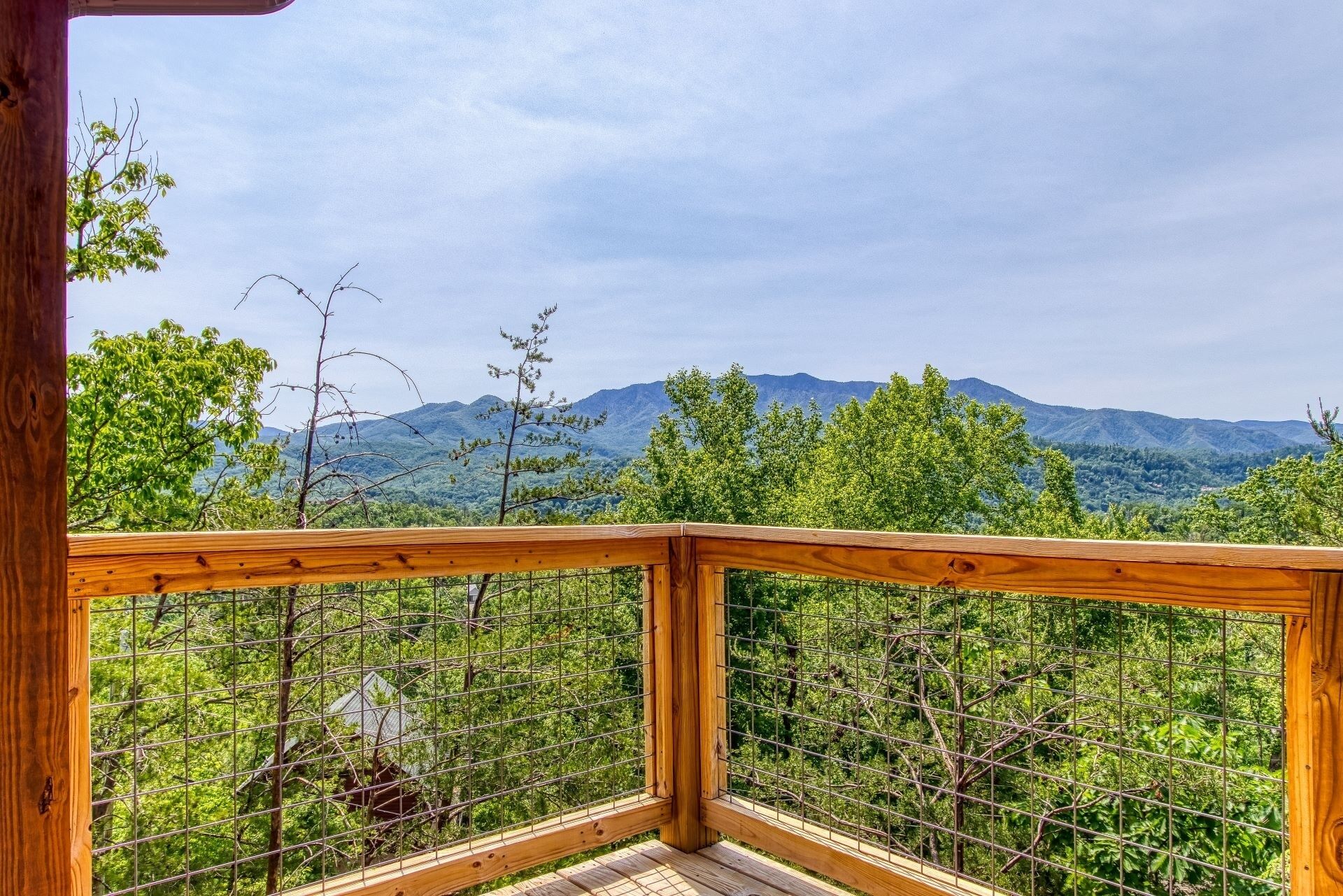 Una terraza de madera con baranda metálica que da a un paisaje montañoso.