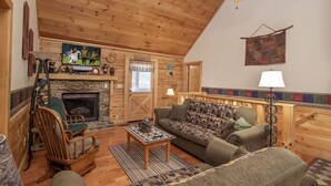 A cozy living room with a fireplace, wooden furniture, and a television.