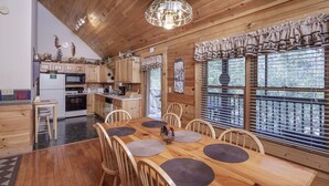 A wooden interior with a dining table, chairs, and a kitchen area.