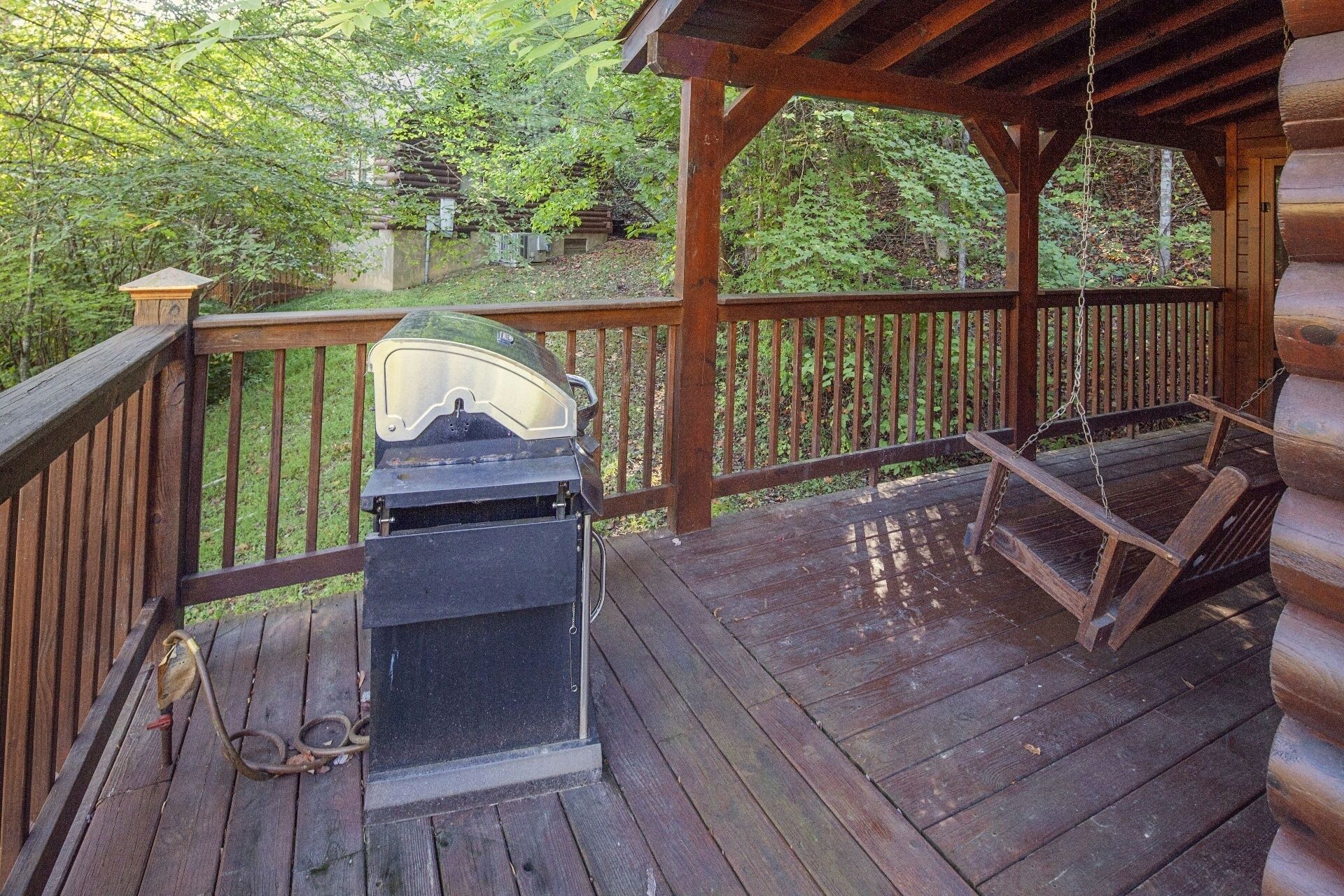 A wooden deck with a grill and a swing.