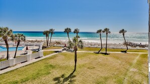 En fantastisk utsikt över stranden med en pool, palmer och en klar himmel.