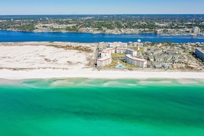 Eine Luftaufnahme eines Küstenresorts mit Strandvillen, einer Marina und einer weiten Wasserfläche.