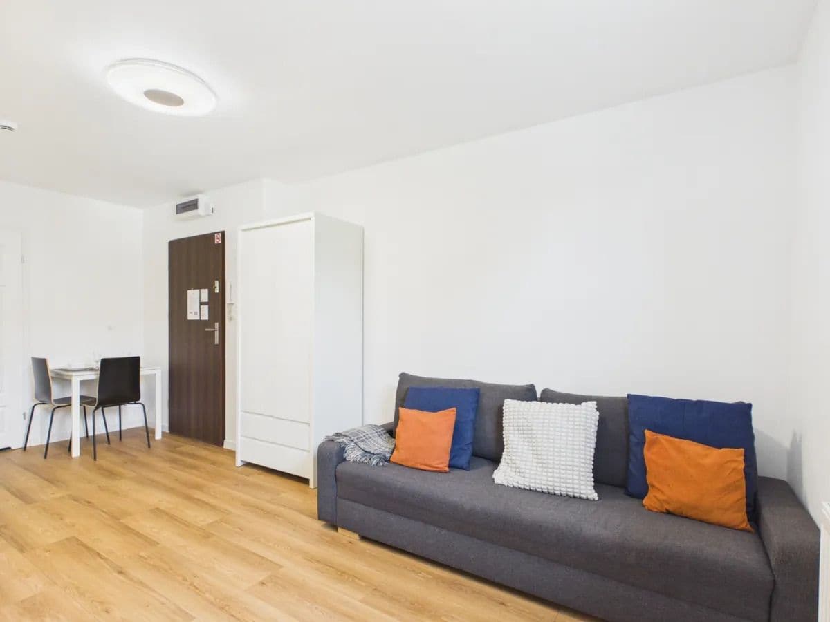 Una sala de estar moderna con un sofá gris, una mesita y dos sillas.